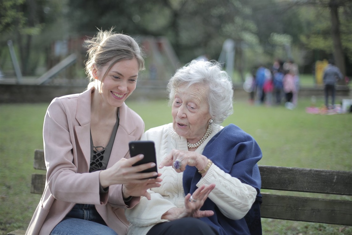 Young woman showing senior woman her smartphone
