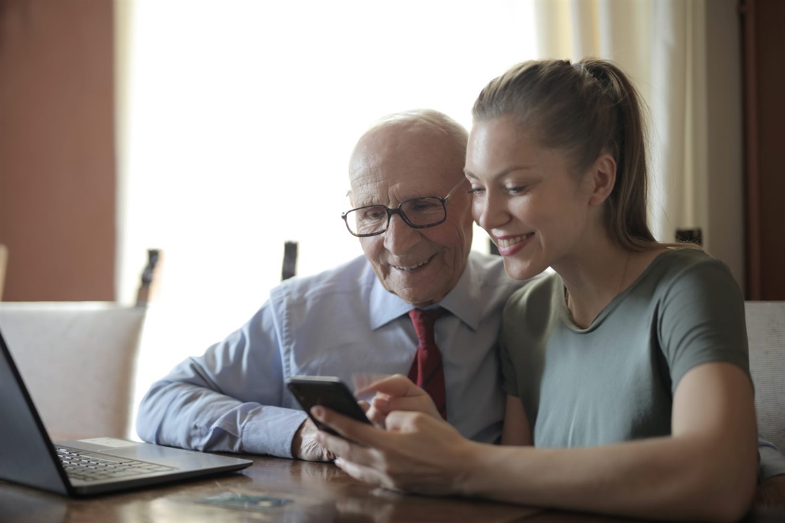 Young woman showing senior man her smartphone